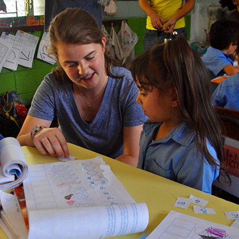 A Brown youth member helps an El Salvadorian child with her school work.
