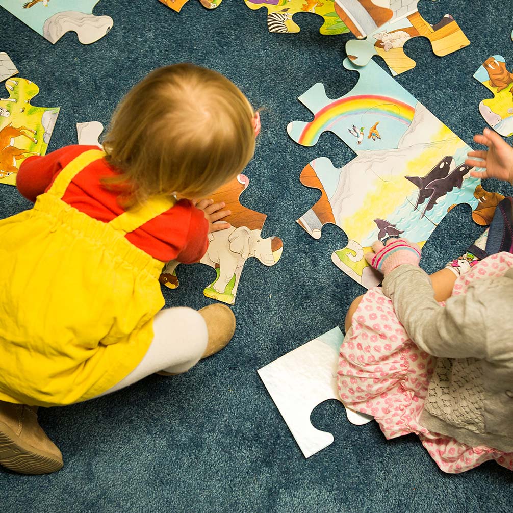 a little girl plays with a puzzle in the nursery