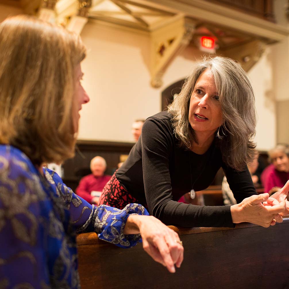 two women converse in worship