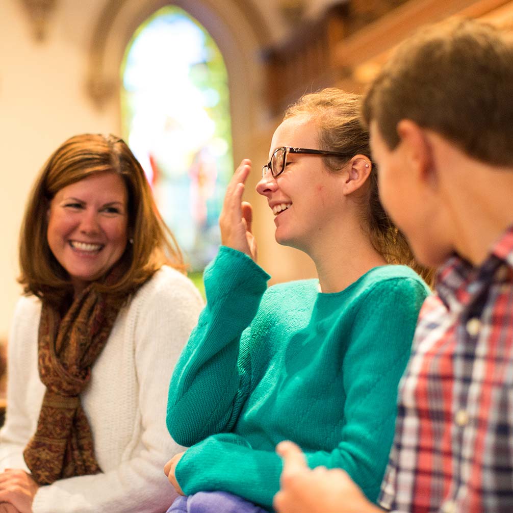 a mother and her two children chatting and laughing before worship