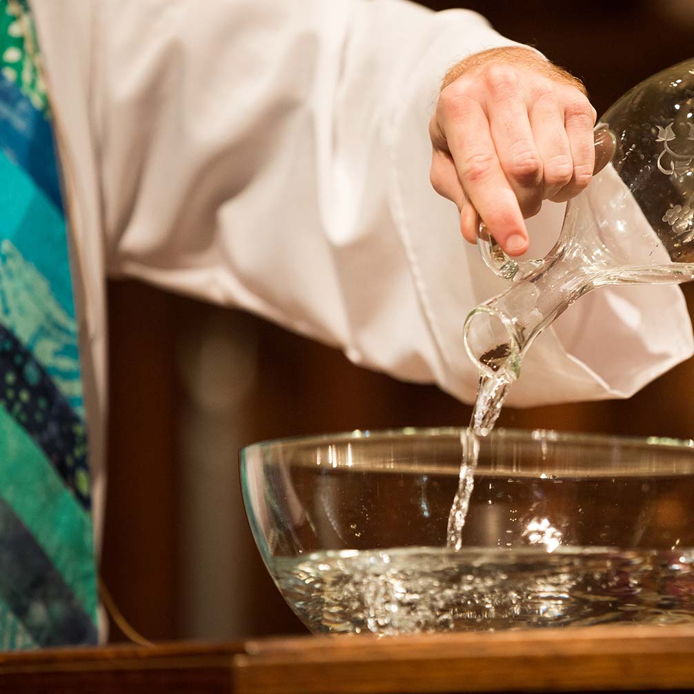 a pastor pours water into the baptismal font