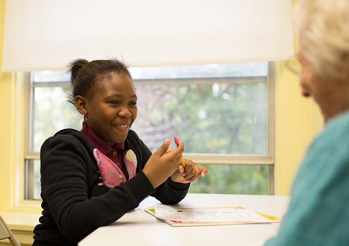 a girl in Brown Memorial's tutoring program smiles during her reading lesson