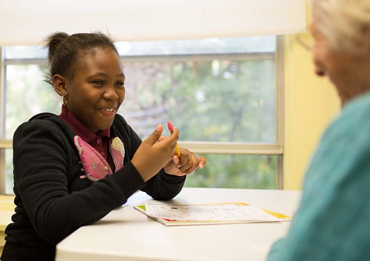 a young girl in Brown Memorial's tutoring program smiles during her reading lesson