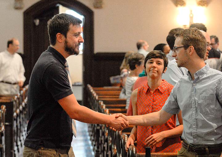 a couple greets a new visitor to church