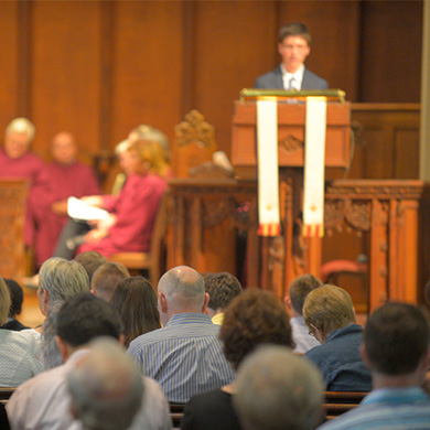 A youth speaks from the pulpit during Sunday worship.
