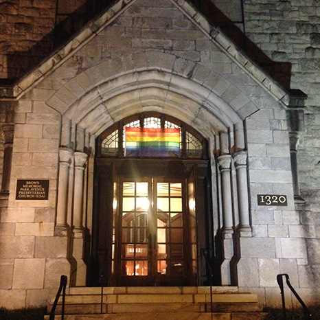 A nighttime view of Brown Memorial's front door with the Sanctuary illuminated inside where the evening prayer service is being held.