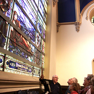People gaze up at one of the large Tiffany stained glass windows in Brown's sanctuary during a windows tour.