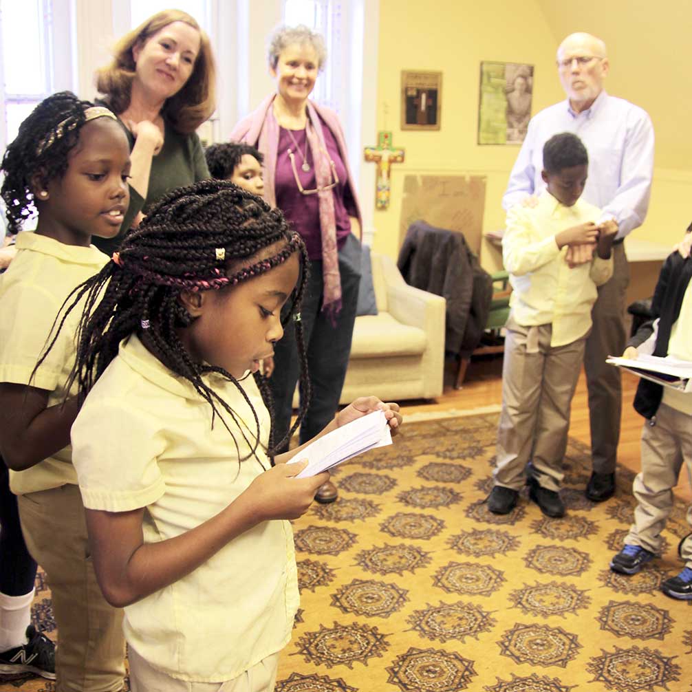 A Brown Memorial Tutoring Program students reads something she has written, with her tutor looking on.