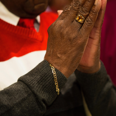 A member of Brown Memorial holds his hands together in prayer.
