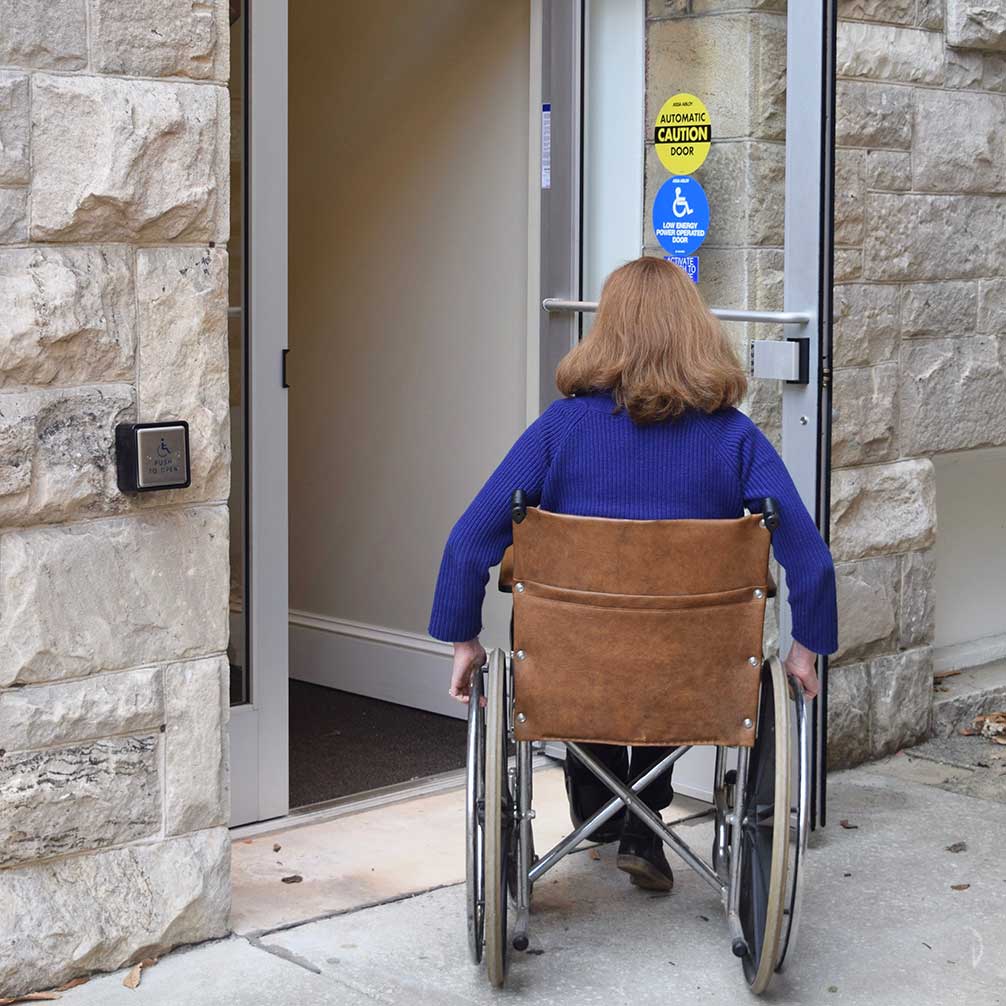 A woman enters the Fellowship Building in a wheelchair.