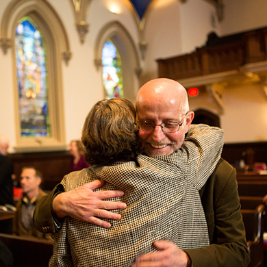 Two members of Brown Memorial hug each other in greeting during Sunday worship.