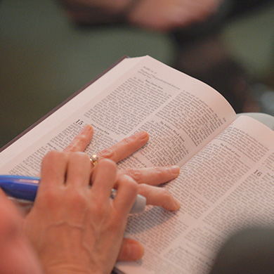 A hand rests on an open bible.