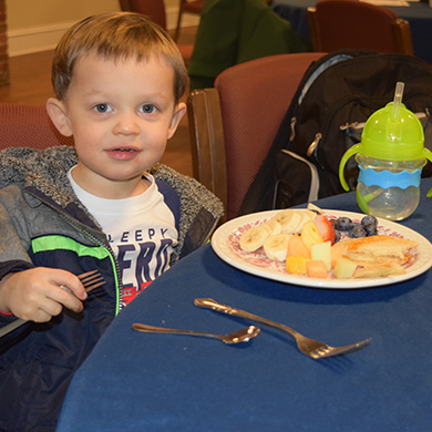 A child in the congregation eats a pancake meal on Fat Tuesday at Brown Memorial.