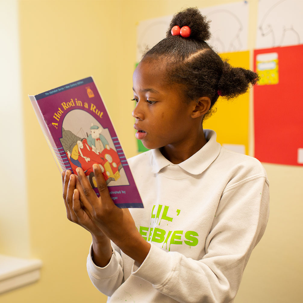 A girl reads a book during a session with the Brown Tutoring Program.