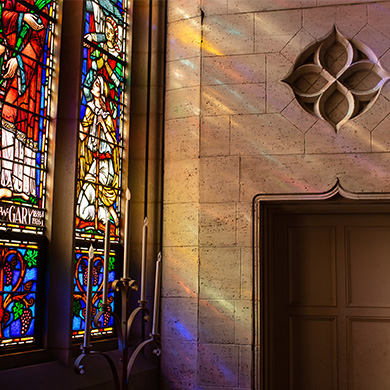 Sun shines through stain glass into the sanctuary.