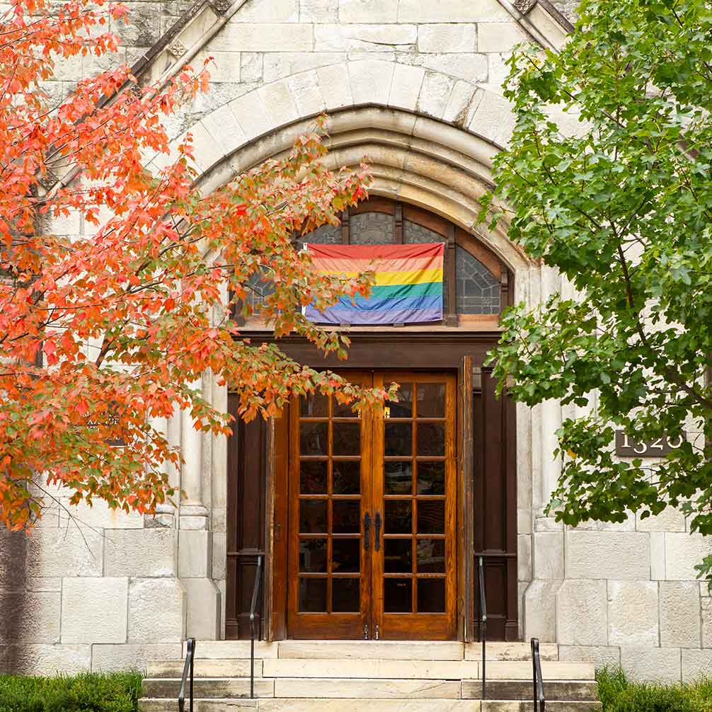 The front door of Brown Memorial with the rainbow flag above the door.