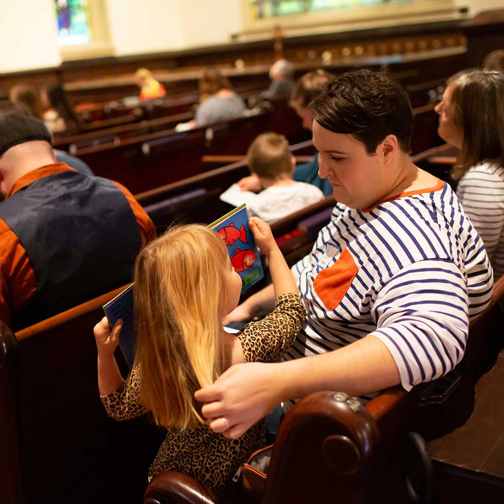 A woman in her young daughter sit together in a pew on Sunday morning.