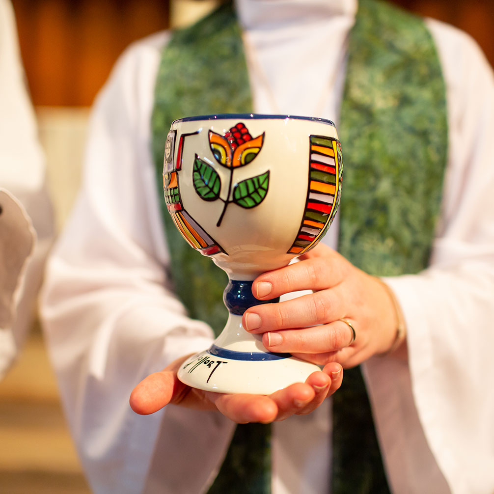 Associate Pastor Michele Ward holds out the communion cup to a visitor.