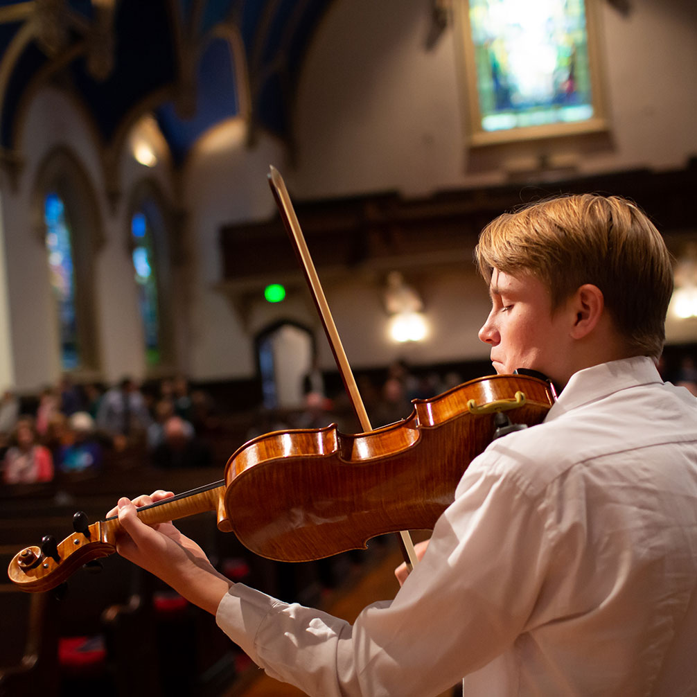 A member of the congregation plays a violin solo during worship.